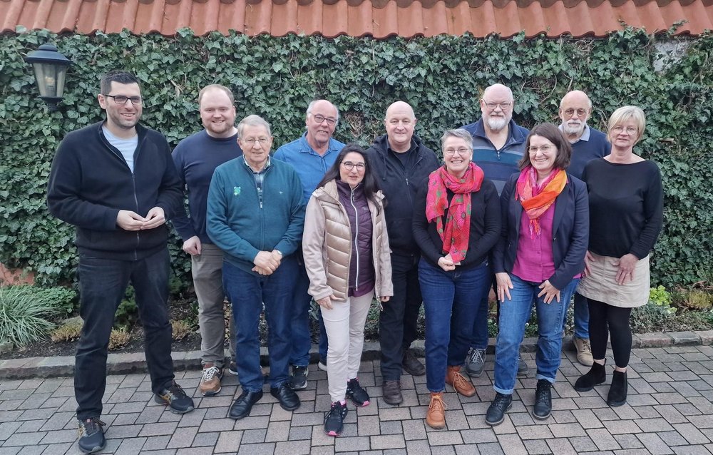 Gruppierung von Menschen vor einer efeubewachsenen Mauer