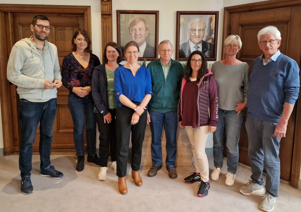 Mitglieder der Kreistagsfraktion Warendorf und Mitarbeiterinnen des GrenzInfoPunktes im Tagungsraum. An der Wand hängt ein Bild von dem niederländischen König Willem-Alexander und ein Bild von Bund vom deutschen Bundespräsidenten Frank-Walter Steinmeier